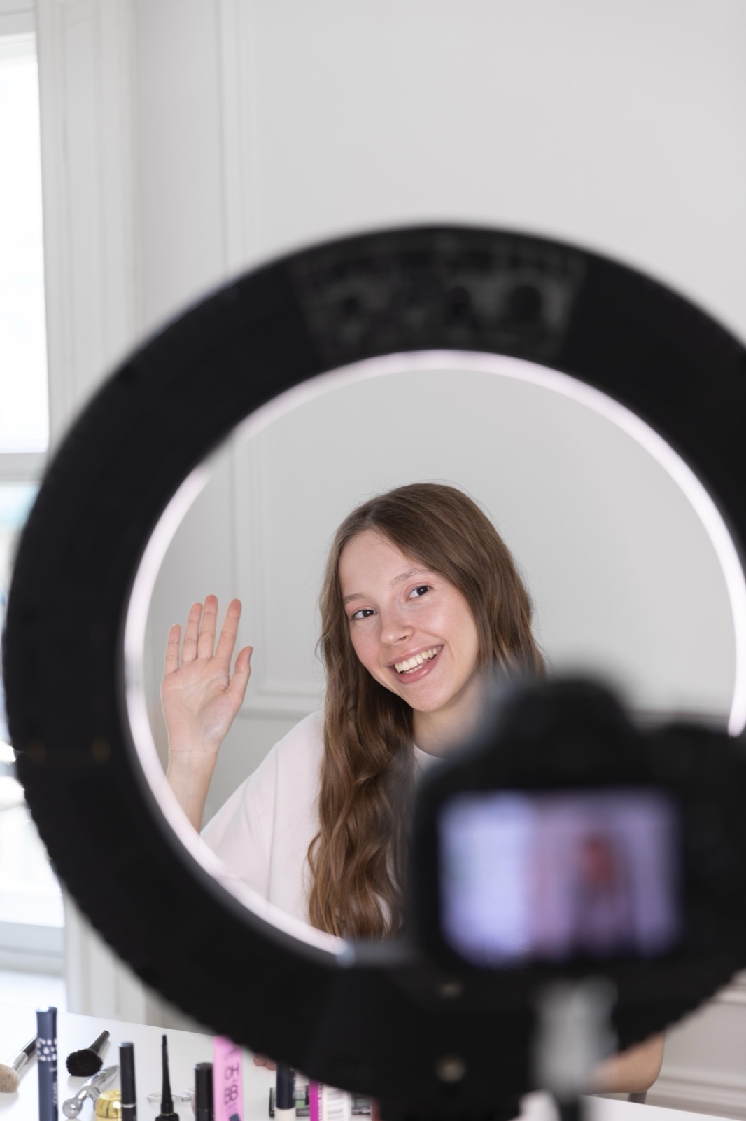 Creator gravando conteúdo com ring light, câmera e celular montados em um tripé simples em casa.