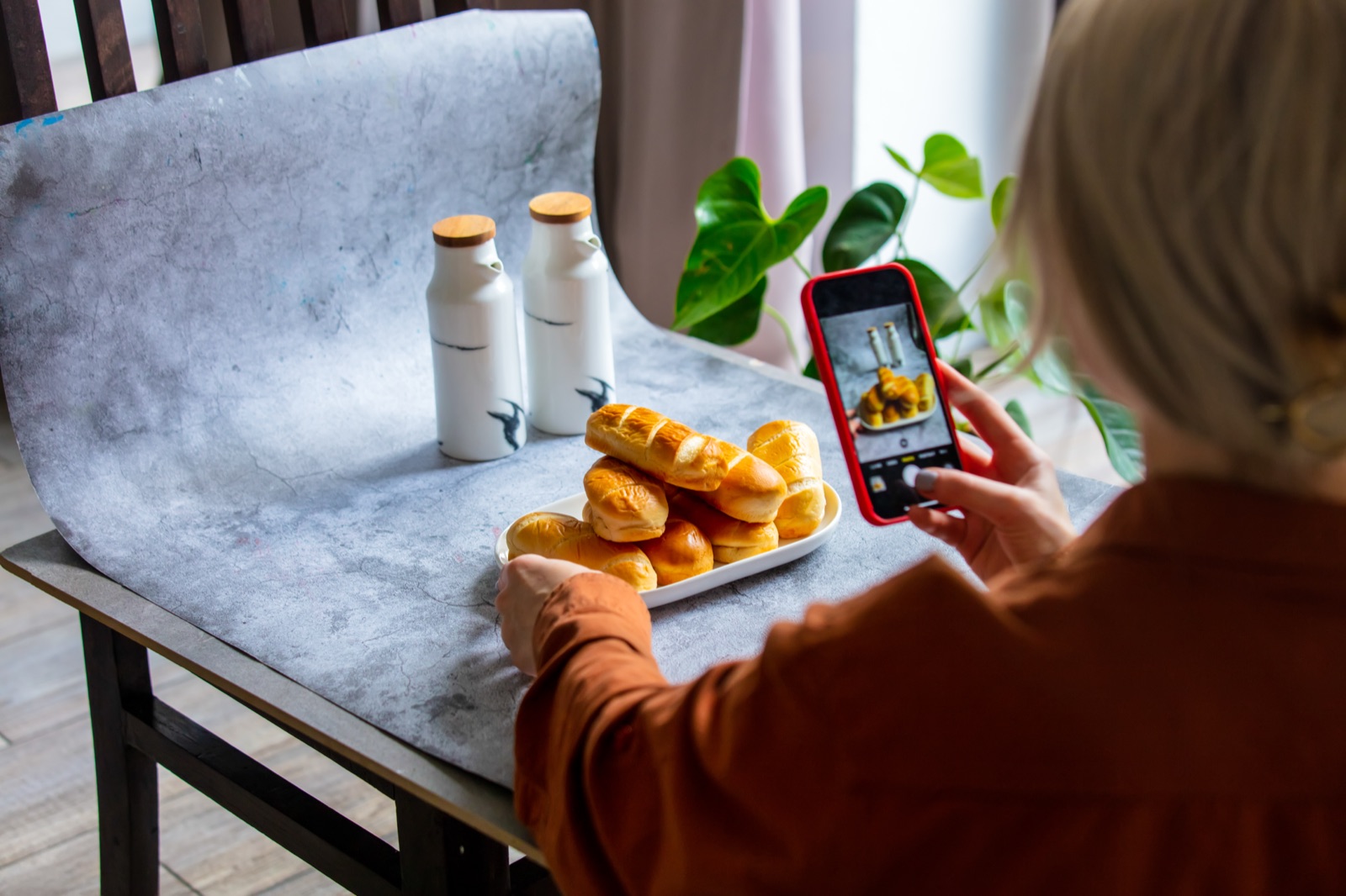Creator fotografando um produto com o celular em um mini estúdio caseiro para vender online.