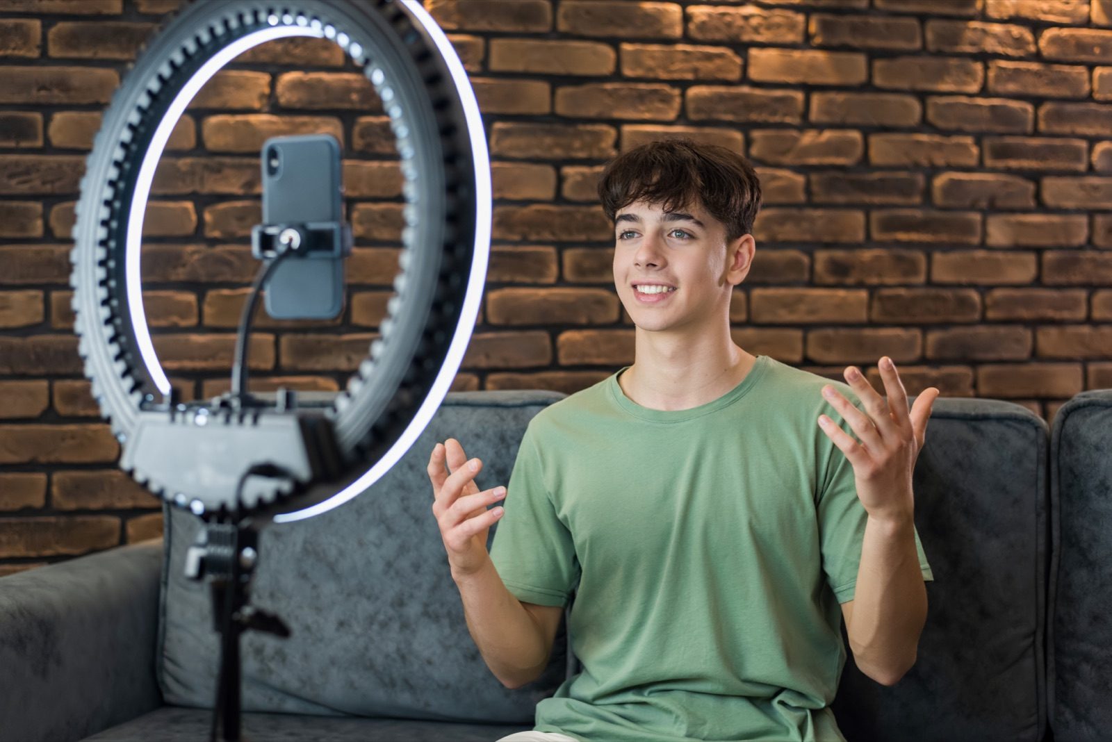 Creator gravando um vídeo para uma marca com ring light e celular em casa, exemplo de conteúdo UGC.