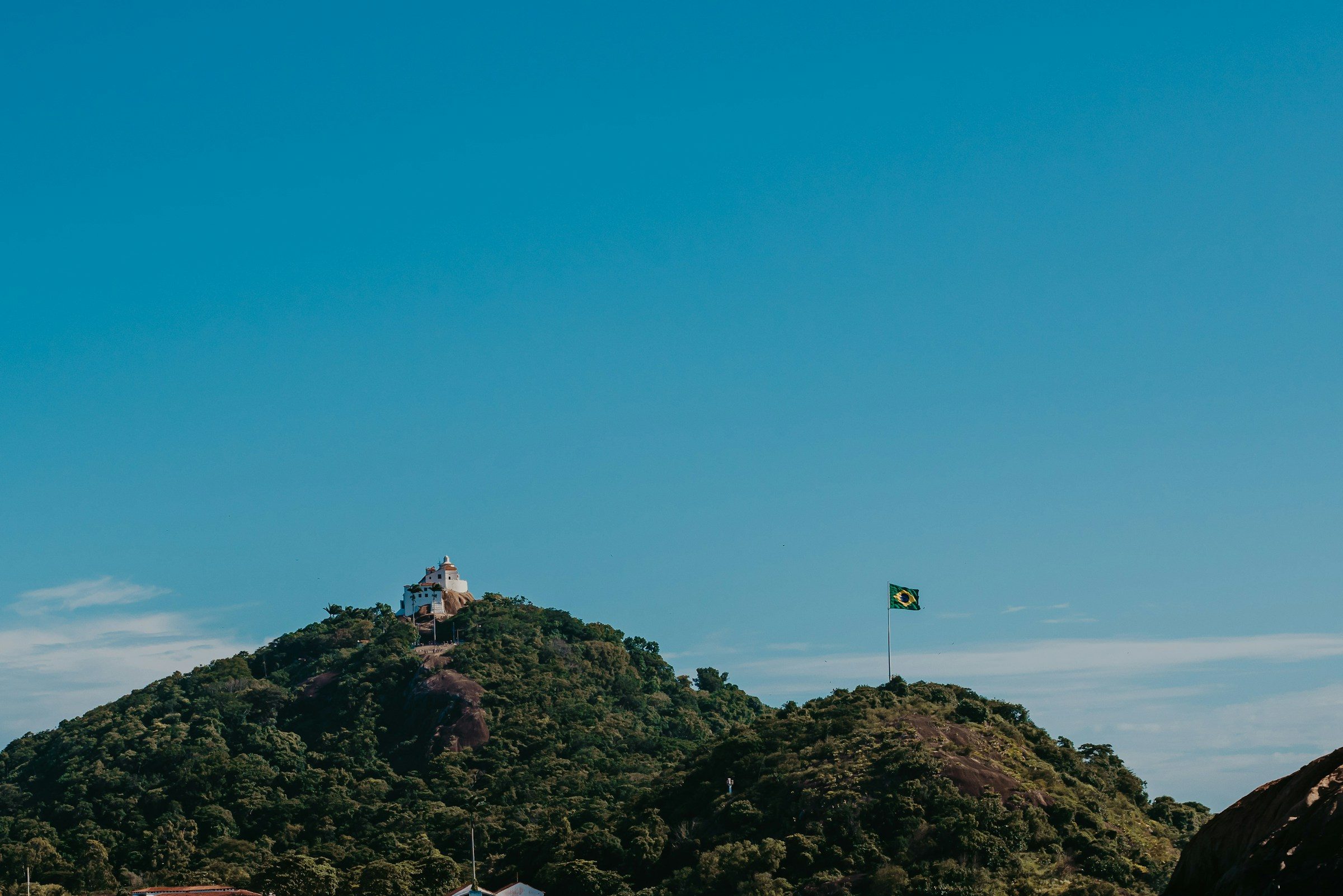 Convento da Penha no alto do morro em Vila Velha, com a bandeira do Brasil ao lado.