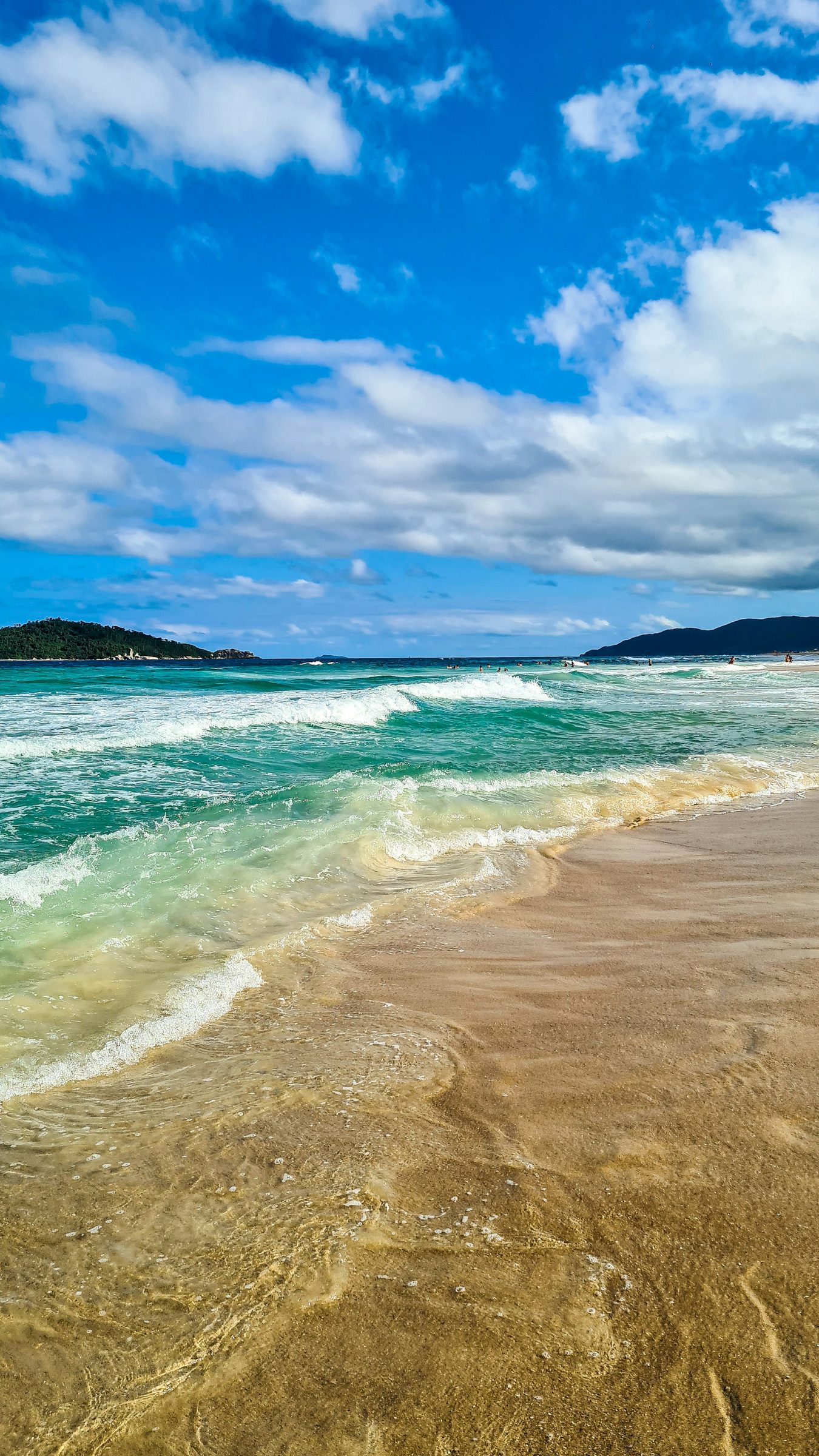Praia de mar aberto com ondas e areia clara em Florianópolis.
