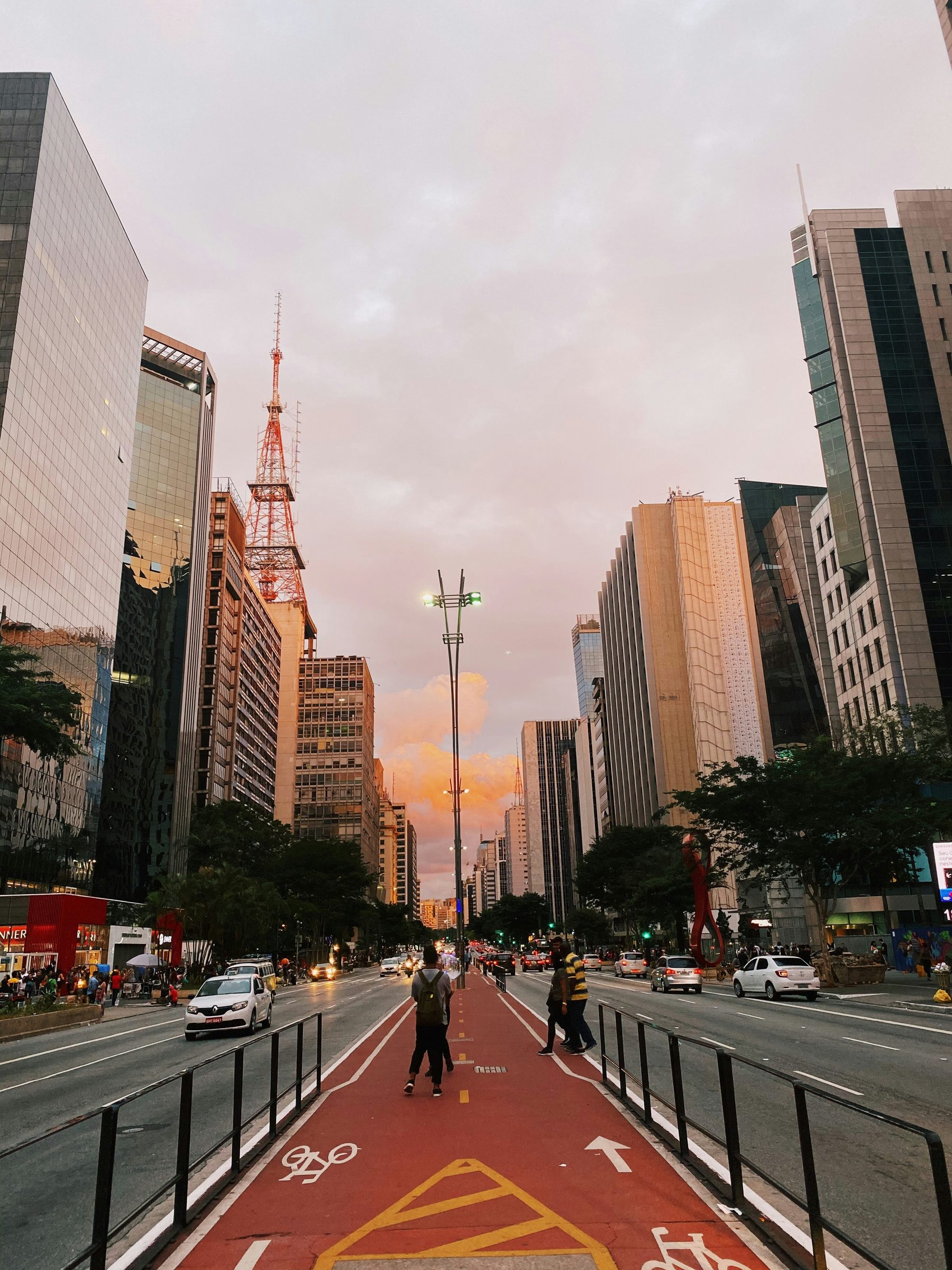 Pessoa parada na ciclovia central da Avenida Paulista, em São Paulo, ao entardecer.