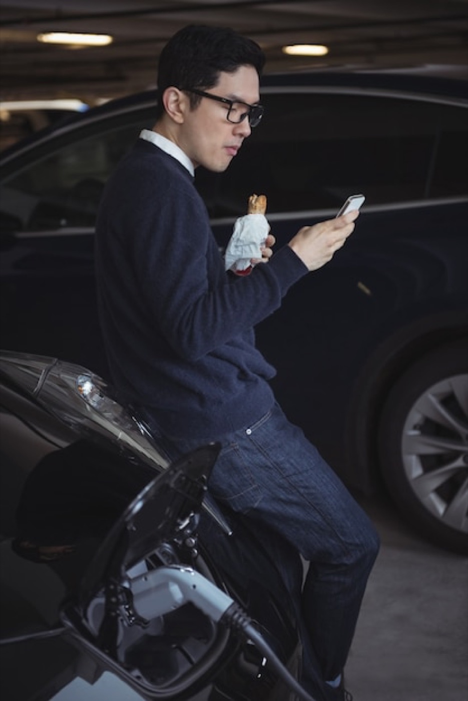 Pessoa usando o smartphone ao lado de um carro em conteúdo automotivo.