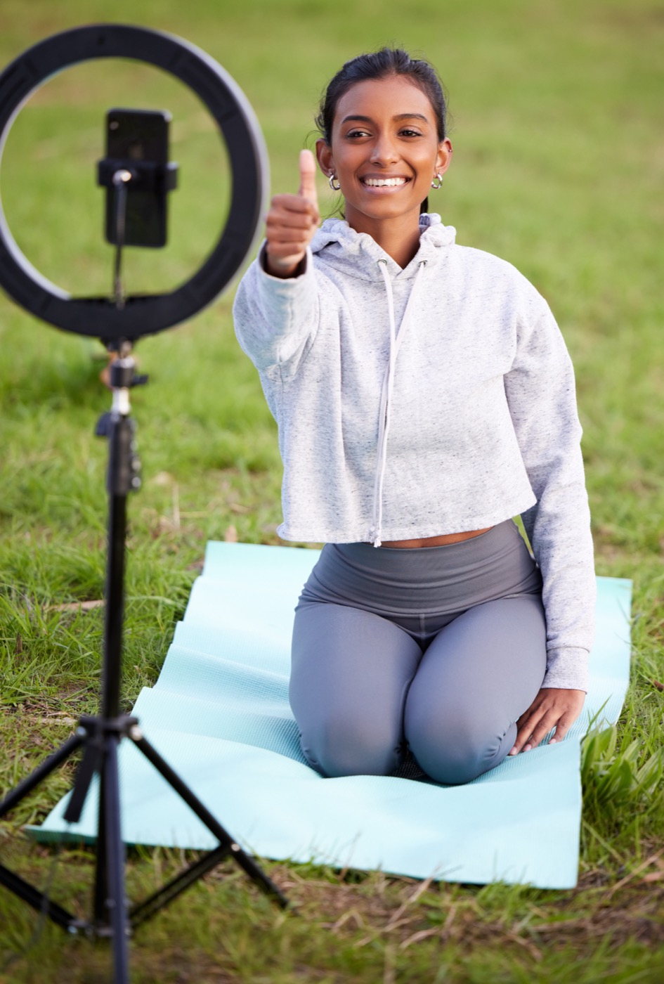 Creator fazendo yoga ao ar livre e gravando conteúdo fitness com ring light.