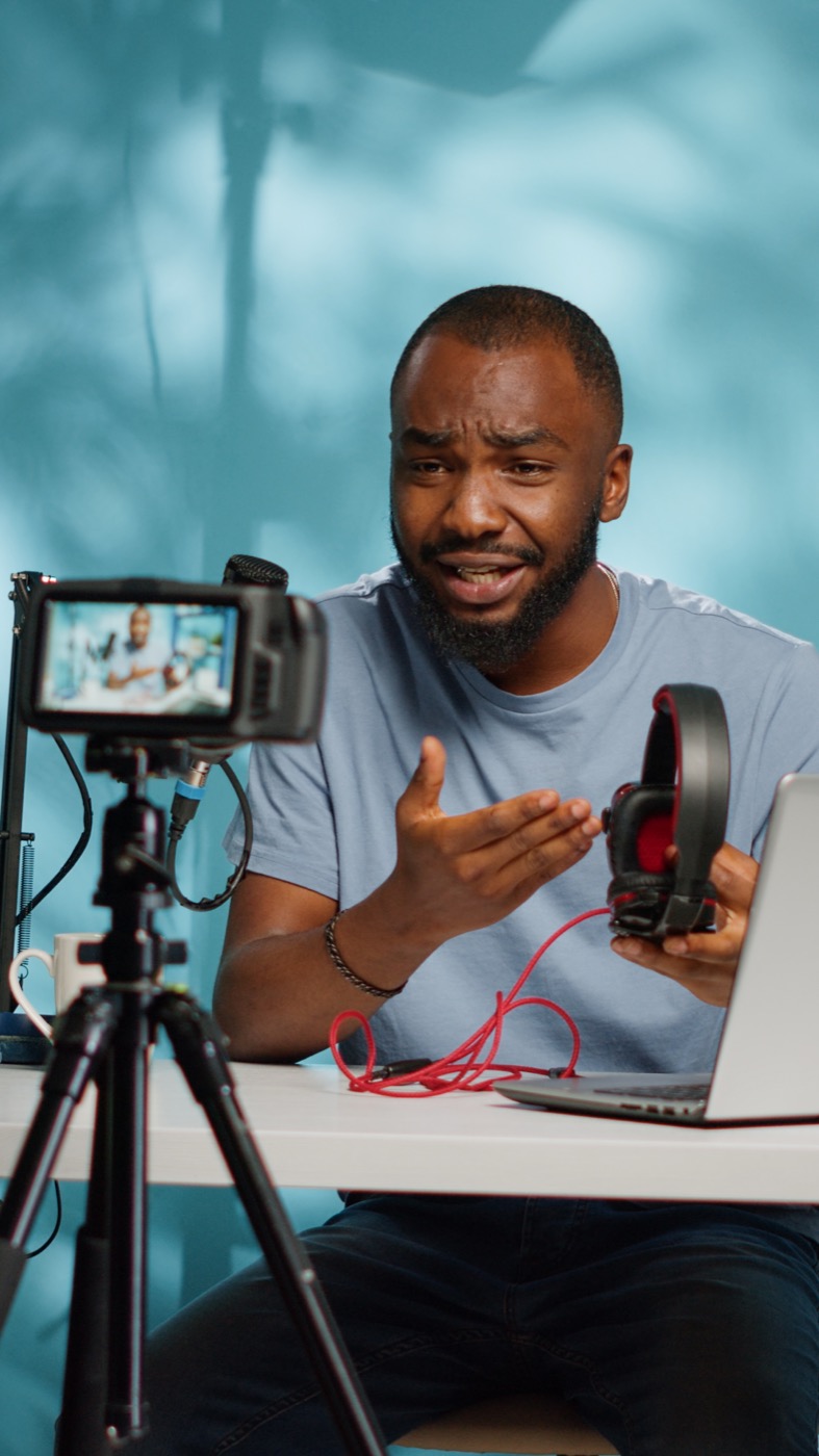 Creator gravando um review de fone de ouvido em estúdio com tripé e microfone.